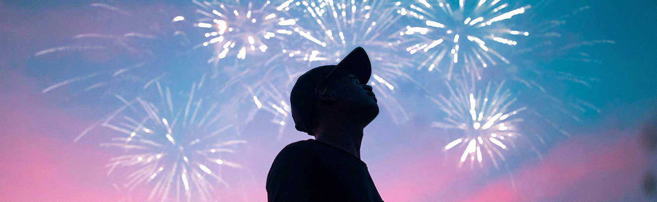 Silhouette of a man in a cap with fireworks in the background