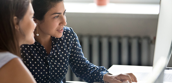 Two ladies working at a desktop computer