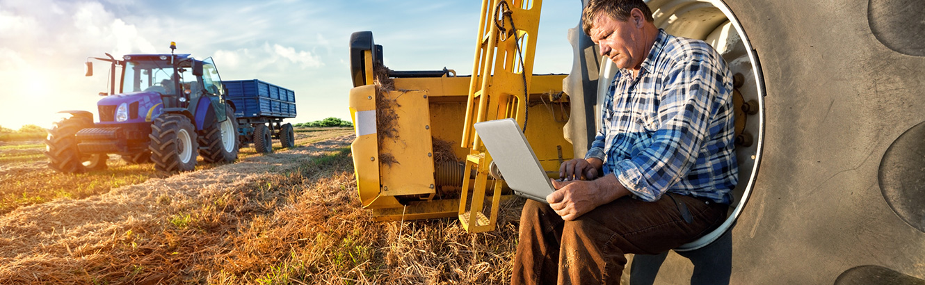 Farmer working on a laptop computer around farm equipment