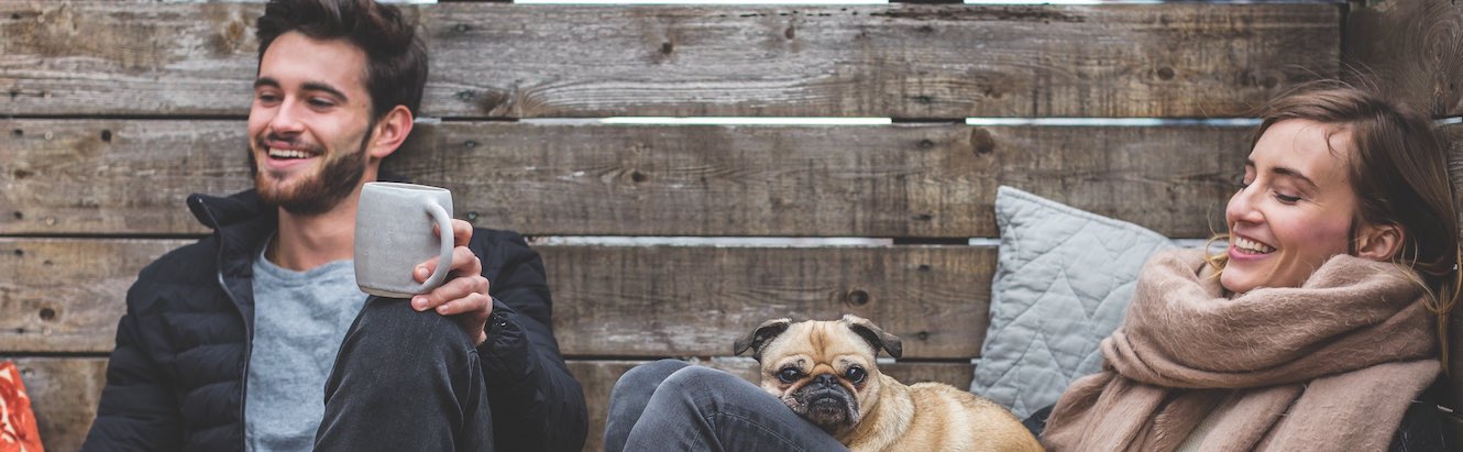 Man and woman with cozy winter mugs and pug