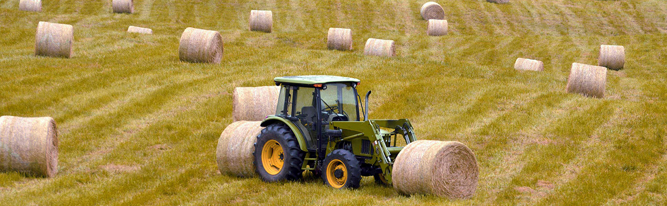 green tractor out in the middle of a hay flied